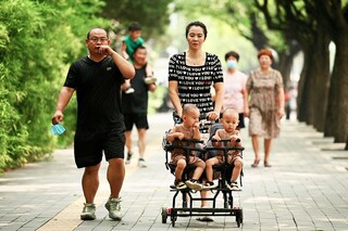A woman pushes a trolley with twins along a street in Beijing on August 2, 2022. China"s population will begin to shrink by 2025, officials said, as family sizes grow smaller and citizens age. Image: Noel Celis / AFP