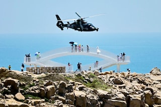 Tourists look on as a Chinese military helicopter flies past Pingtan island, one of mainland China"s closest point from Taiwan, in Fujian province, following US House Speaker Nancy Pelosi"s visit. Image: Hector Retamal/AFP&nbsp