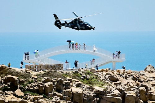 Tourists look on as a Chinese military helicopter flies past Pingtan island, one of mainland China"s closest point from Taiwan, in Fujian province, following US House Speaker Nancy Pelosi"s visit. Image: Hector Retamal/AFP&nbsp