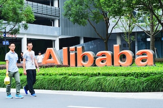 Staff members walk past a logo of Chinese ecommerce giant Alibaba at its headquarters in Hangzhou in China"s eastern Zhejiang province. Image: AFP / China OutÂ 