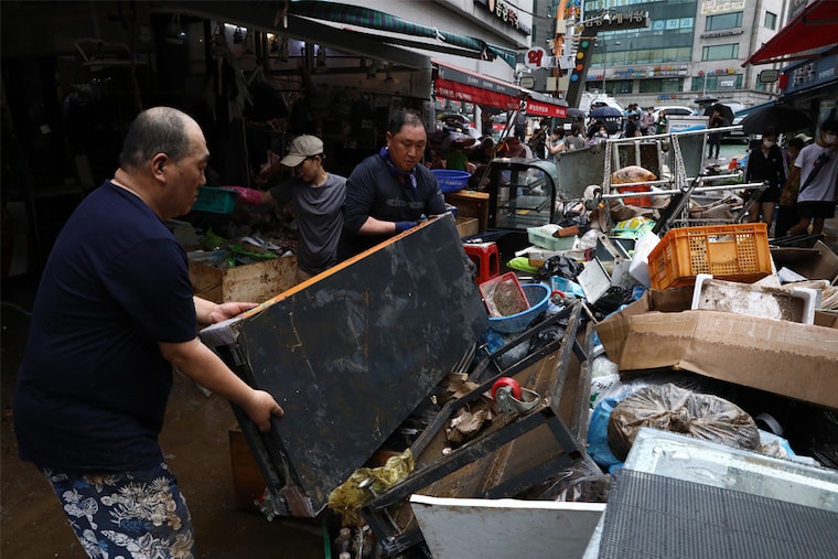 People clean up debris at a traditional market damaged by a flood after torrential rain on August 09, 2022, in Seoul, South Korea. Government officials said that the heaviest rainfall in 80 years pounded Seoul and surrounding regions, leaving seven people dead and six others missing and flooding homes, vehicles, buildings and subway stations.