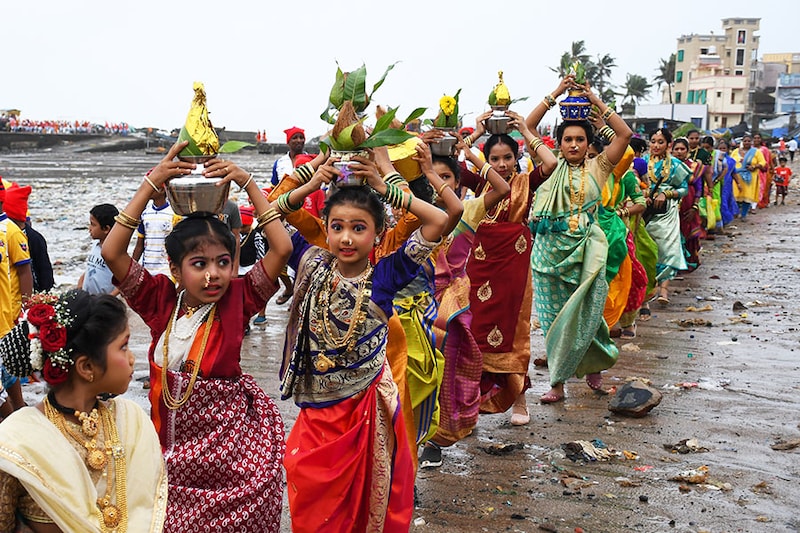 Fisherwomen in traditional attire carry an offering of pots holding coconuts during the Narali Poornima celebration in Mumbai, on August 11, 2022. The fishing community in the coastal region of Maharashtra offer coconuts and prays to the sea gods for a safe and plentiful fishing season.