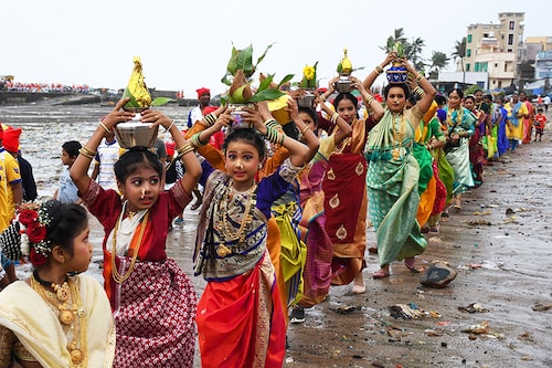 Fisherwomen in traditional attire carry an offering of pots holding coconuts during the Narali Poornima celebration in Mumbai, on August 11, 2022. The fishing community in the coastal region of Maharashtra offer coconuts and prays to the sea gods for a safe and plentiful fishing season.