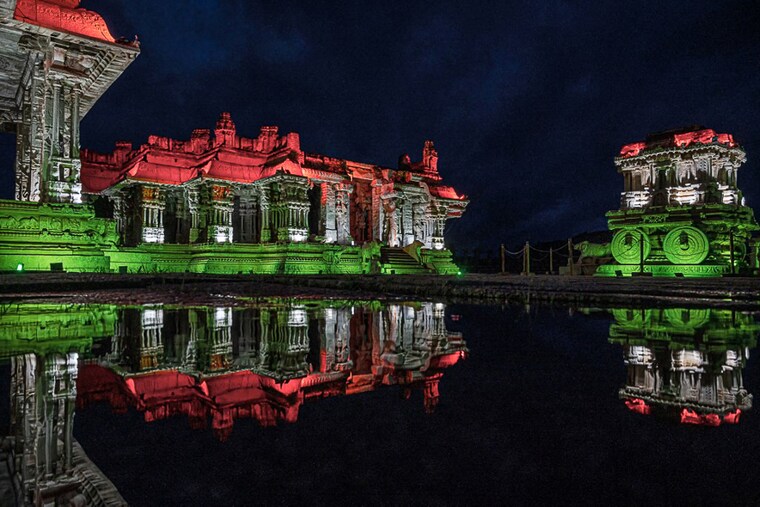 The Hampi temple complexes and the famed stone chariot, a UNESCO World Heritage site, are seen illuminated with the colours of the Indian flag on the eve of the country"s 75th Indian Independence Day celebrations, Vijayanagara, Karnataka.