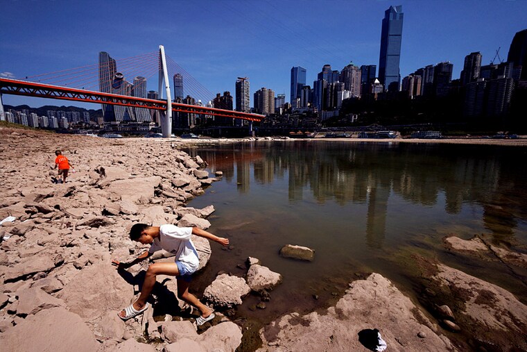 A boy climbs on the dried-up riverbed of the Jialing river, a tributary of the Yangtze, that is approaching record-low water levels in Chongqing, China, August 18, 2022.