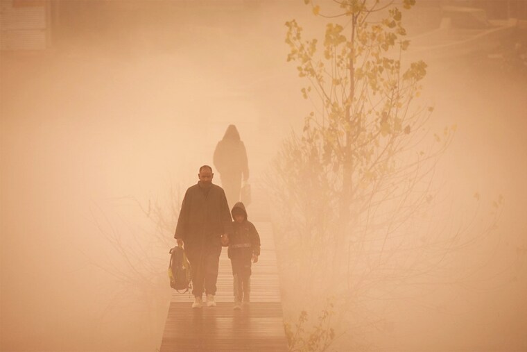 A child accompanied by an elder cross a footbridge as they walk towards his school amid foggy conditions in Srinagar on December 2, 2022.
