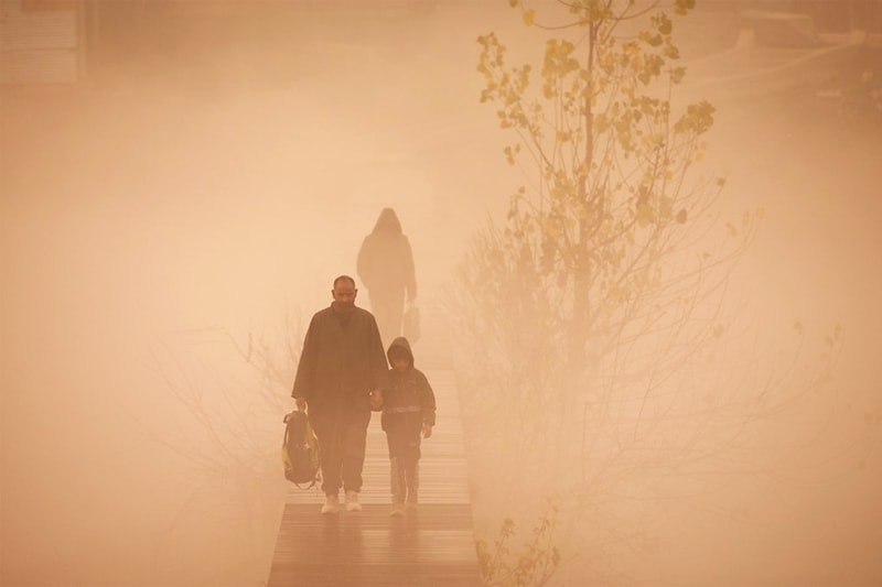 A child accompanied by an elder cross a footbridge as they walk towards his school amid foggy conditions in Srinagar on December 2, 2022.
