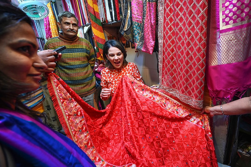 German Foreign Minister Annalena Baerbock (in red) visits Kinari Bazaar, famed for its embroidered and sequinned dress materials in Chandni Chowk, New Delhi on December 5, 2022. Baerbock then made the payment using UPI to experience how digital payments are used at a local level.