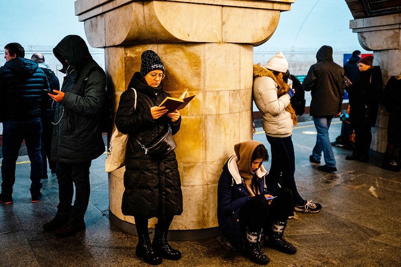 A woman reads a book while civilians take shelter inside a metro station during an air raid alert in the centre of Kyiv on December 16, 2022, amid the Russian invasion of Ukraine. A fresh barrage of Russian strikes hit cities across Ukraine early on December 16, 2022, cutting water and electricity in major cities and piling pressure on Ukraine"s grid with temperatures below freezing.