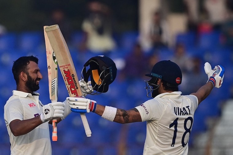 India"s Cheteshwar Pujara (L) celebrates after scoring a century (100 runs) with Virat Kohli. The duo were captured playing during the third day of the first cricket test match between Bangladesh and India, at the Zahur Ahmed Chowdhury Stadium in Chittagong, on December 16, 2022.