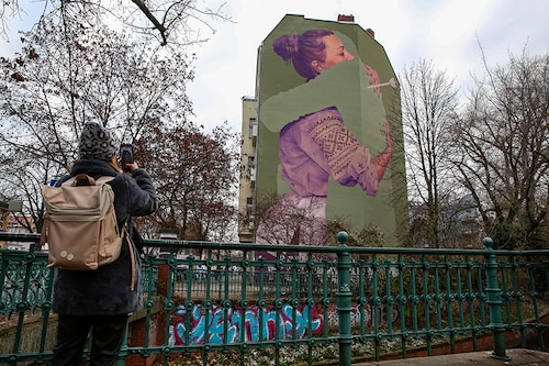 A Ukrainian woman takes a photo of a mural by the innerfields art collective titled "Absent," depicting a Ukrainian woman who lost a loved one to war, on December 16, 2022, in Berlin, Germany. Tens of thousands of Ukrainians are estimated to have been killed since Russia launched its large-scale invasion on February 24, but an official civilian or military death toll has not been given. Image: Adam Berry/Getty Images