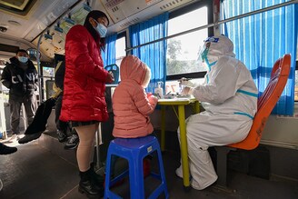 Doctors treat residents on a mobile diagnosis and treatment vehicle for fever at an industrial park in Nanjing, Jiangsu province, China on December 21, 2022. Covid-19 cases are rising across China, especially in rural and underdeveloped parts of the country.