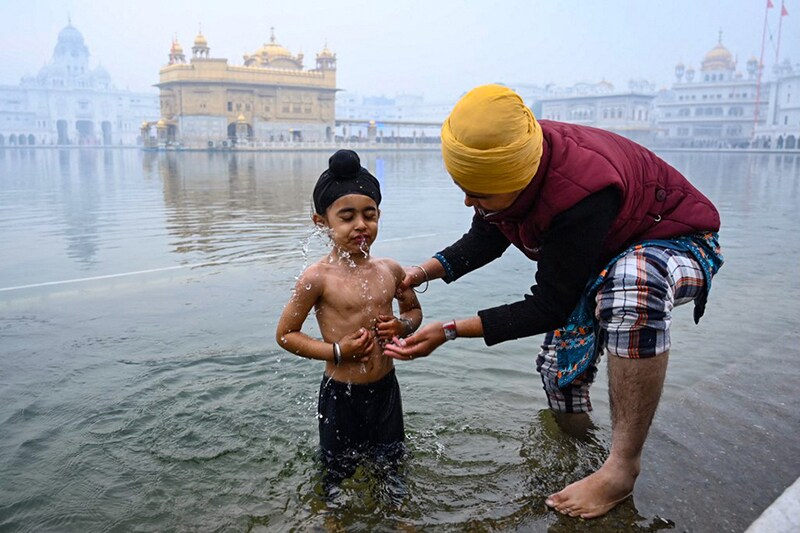 A young Sikh devotee takes a bath in the holy Sarovar (pool) on the occasion of the birth anniversary celebrations of the tenth Guru of the Sikhs, Guru Gobind Singh, at the Golden Temple in Amritsar on December 29, 2022.