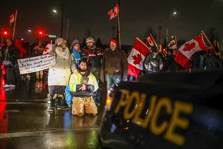 A protester kneels as truckers and supporters continue blocking access to the Ambassador Bridge which connects Detroit and Windsor, in protest against coronavirus disease (Covid-19) vaccine mandates, in Windsor, Ontario, Canada on February 11, 2022.