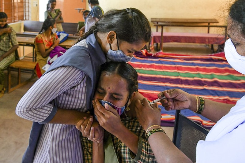 A student winces as she receives a dose of the Covaxin vaccine at the Nelamangala Government High School and Junior College in Bangalore on January 3, 2022. A special Covid-19 vaccination drive for teens in the 15 to 18 age group was launched across the country from today morning, amid clear signs of the beginning of a fresh Covid wave in the country.