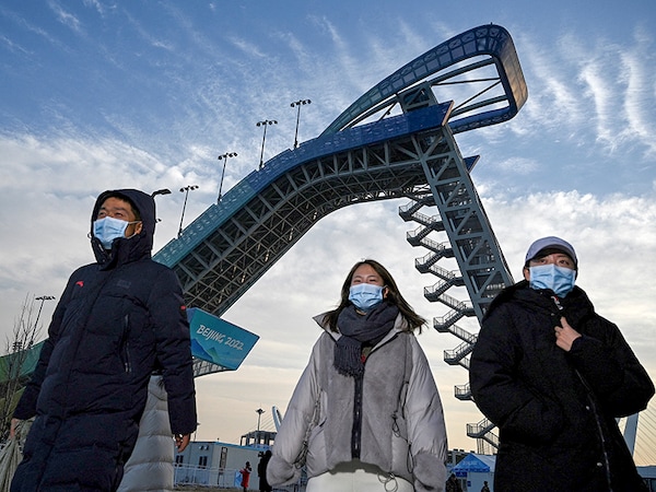 People walk near the Shougang Big Air venue, which will host the big air freestyle skiing and snowboarding competitions at the Beijing 2022 Winter Olympics. Image: Noel Celis / AFP