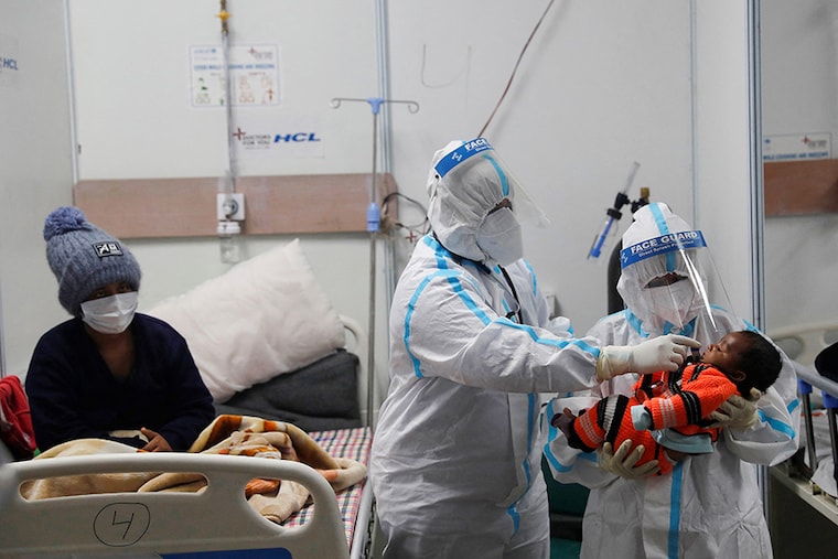 Medical workers wearing personal protective equipment (PPE) check temperature of an infant, whose mother is suffering from coronavirus disease (COVID-19), inside a care centre at an indoor sports complex, amidst the spread of the disease, in New Delhi, India, January 5, 2022.