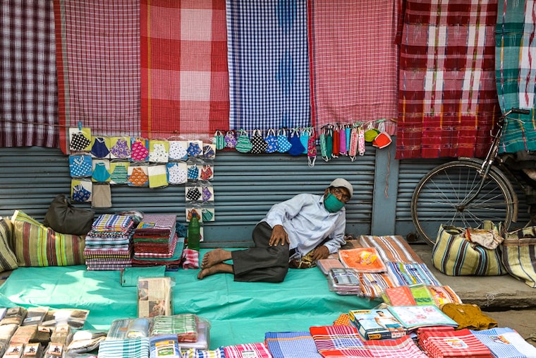 A street vendor awaits a customer at his makeshift stall on a day of curfew and closed shops at a major market in Siliguri on January 9, 2022. Itinerant vendors are worst hit by the new restrictions from authorities to curb the spread of the Covid-19 virus.