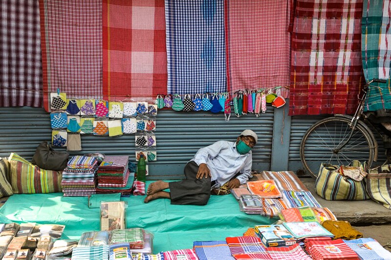 A street vendor awaits a customer at his makeshift stall on a day of curfew and closed shops at a major market in Siliguri on January 9, 2022. Itinerant vendors are worst hit by the new restrictions from authorities to curb the spread of the Covid-19 virus.