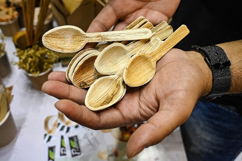 An exhibitor shows spoons made from leaf sheaths naturally shed by arecanut (palm) trees during the Plastic Vikalp mela ("alternative to plastic" fair) in New Delhi on July 1, 2022. India imposed a ban on many single-use plastics on Friday in a bid to tackle plastic choking rivers and poisoning wildlife, but experts say it faces severe headwinds from unprepared manufacturers and consumers unwilling to pay more.