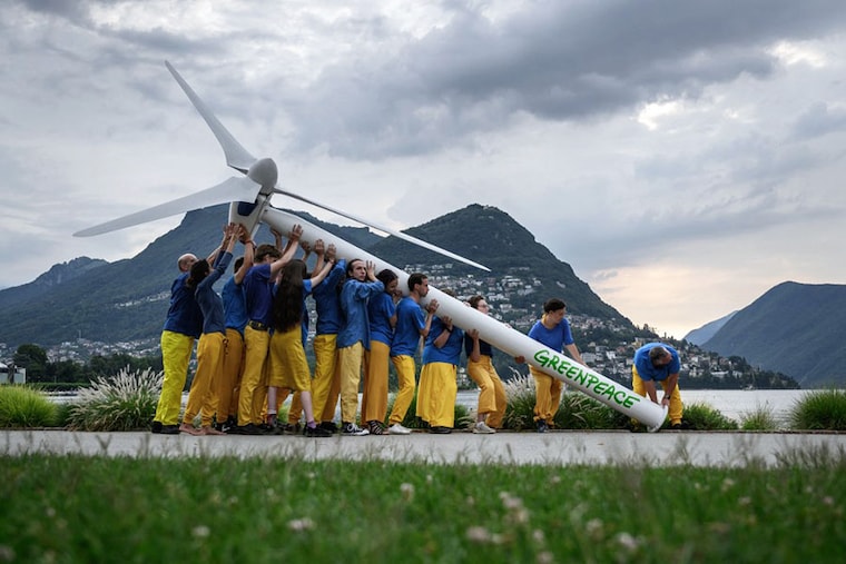 Greenpeace activists raise a factice wind turbine on the edge of Lake Lugano during a demonstration calling for a sustainable reconstruction of Ukraine, ahead of a two-day Ukraine Recovery Conference in Lugano on July 4, 2022. Ministers from dozens of countries and international organisations" leaders will gather in the city of Lugano with the aim of providing a roadmap for the war-ravaged country"s recovery.