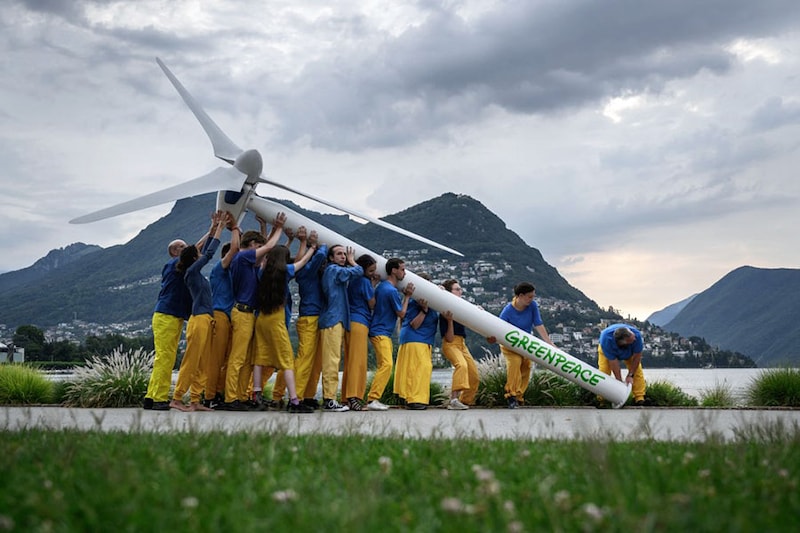 Greenpeace activists raise a factice wind turbine on the edge of Lake Lugano during a demonstration calling for a sustainable reconstruction of Ukraine, ahead of a two-day Ukraine Recovery Conference in Lugano on July 4, 2022. Ministers from dozens of countries and international organisations" leaders will gather in the city of Lugano with the aim of providing a roadmap for the war-ravaged country"s recovery.