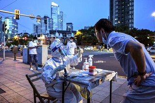 A health worker takes a swab sample from a man to test for the Covid-19 coronavirus on a street next to a residential area in the Jing"an district of Shanghai on July 5, 2022. Image: Hector RETAMAL / AFP