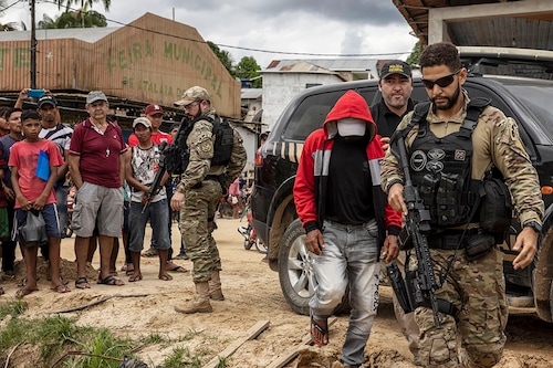 Police escort Amarildo Oliveira, who confessed to killing Bruno Pereira and Dom Phillips, in Atalaia do Norte, Brazil, June 15, 2022. The murders of Pereira, who wanted to protect the Amazon and its Indigenous people, and Phillips, who wanted to show how Indigenous communities were trying to defend themselves from poachers, is the story of two men killed while pursuing their passions. (Victor Moriyama/The New York Times)