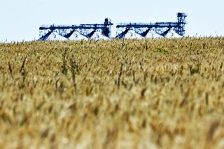 A photograph shows a grain elevator behind a wheat field in Ukraine"s eastern region of Donbas, on July 1, 2022, amid Russia"s military invasion launched on Ukraine. Between a lack of fuel and the risk of being bombed, some Ukrainian farmers are wondering how they will harvest their fields as the period for certain crops approaches in July. Image: Genya SAVILOV / AFP