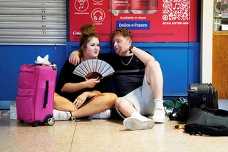 A rail passenger uses a fan to cool down as they sit with their belongings at Euston train station in central London, on July 19, 2022, as services were cancelled due to a trackside fire, and as the country experiences an extreme heat wave.
Image: Niklas Halle"n / AFP