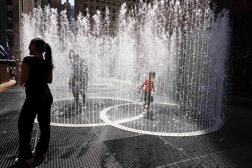 People play in the water-based sculpture of artist Jeppe Hein titled "Changing Spaces" at Rockefeller Center Plaza in New York City on July 19, 2022, as a heat wave continues throughout Europe and North America. Image: Yuki IWAMURA / AFP