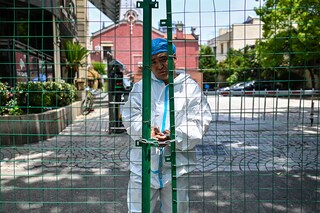 A worker padlocks fencing securing a residential area under Covid-19 lockdown in the Xuhui district of Shanghai on June 8, 2022. Image:Â Hector Retamal / AFP