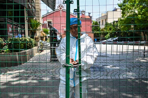 A worker padlocks fencing securing a residential area under Covid-19 lockdown in the Xuhui district of Shanghai on June 8, 2022. Image:Â Hector Retamal / AFP A worker padlocks fencing securing a residential area under Covid-19 lockdown in the Xuhui district of Shanghai on June 8, 2022. Image:Â Hector Retamal / AFP