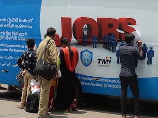Unemployed youths fill application forms to access job openings in the private sector outside an "employment van" during an initiative by TMI foundation and Hyderabad city police, in Hyderabad. Image: NOAH SEELAM / AFP<br>