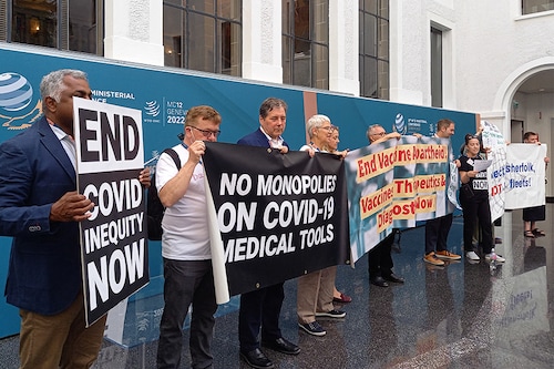 Non-governmental organisation members shout slogans and hold banners as they stage a protest in the World Trade Organization headquarters" central atrium during the second day of a WTO Ministerial Conference in Geneva on June 13, 2022. (Image: Robin MILLARD / AFP)