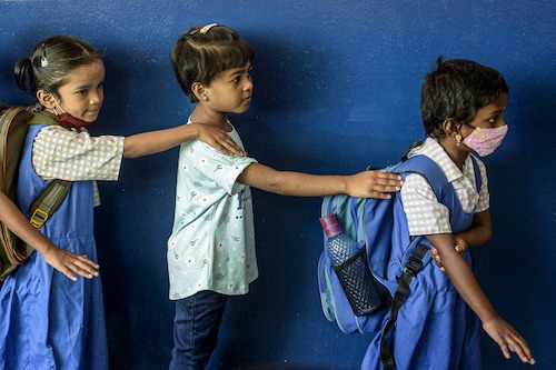 Students await their turn to enter a classroom on the first day of the new academic year at a government primary school in Hyderabad on June 13, 2022. Parents thronged shops along with their children over the weekend, shopping for school uniforms, books, and stationery items for the new academic year.