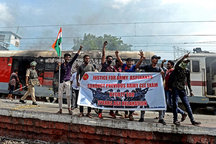 Protesters shout slogans after setting a train on fire during a demonstration against the government"s new "Agnipath" recruitment scheme for the Army, Navy, and Air Force at a railway station in Secunderabad on June 17, 2022.