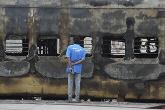 A train coach attender inspects a carriage set on fire by protestors demonstrating against the government"s new "Agnipath" recruitment scheme for the Army, Navy, and Air Forces at a railway station in Secunderabad on June 17, 2022.