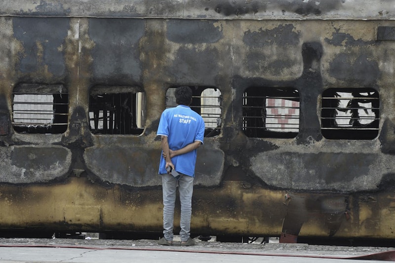 A train coach attender inspects a carriage set on fire by protestors demonstrating against the government"s new "Agnipath" recruitment scheme for the Army, Navy, and Air Forces at a railway station in Secunderabad on June 17, 2022.