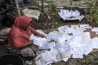 A woman dries the documents that were saved from her home that was submerged in flood water, in Barpeta village, Assam, on June 17, 2022. Devastating floods and landslides have affected over 30 lakh people in 32 districts of the state so far, according to the state"s disaster management authorities.