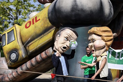 Environmental activists, wearing masks mimicking EU leaders, EU Commission President Ursula von der Leyen and France"s President Emmanuel Macron,   protest to call on EU leaders to exit the Energy Charter Treaty (ECT) near the European headquarters in Brussels in May, 2022. Image: Kenzo TRIBOUILLARD / AFP)