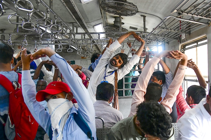 An instructor guides passengers to do yoga while commuting on a local train to celebrate the International Day of Yoga in Mumbai on June 21, 2022. More than 75 instructors conducted sessions in Mumbai local trains on this day whose theme this year is "Yoga for Humanity"