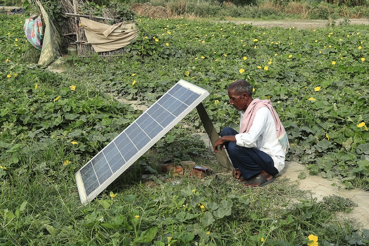 A farmer charges his phone through a solar energy panel placed outside a farm settlement along the Yamuna river in Delhi on the World Sustainable Energy Day on June 22, 2022. The average solar tariff in India was 34% lower than the global weighted average in 2020, according to Bloomberg. India also had the lowest country-level installed cost for solar and wind in 2020.