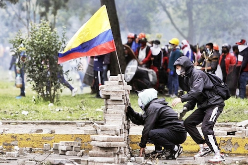 Demonstrators stand behind a barricade during clashes with riot police at the El Ejido park, in Quito, on June 24, 2022, in the framework of indigenous-led protests against the government. Ecuador"s government and Indigenous protesters accused each other of intransigence as thousands gathered for a 12th day of a fuel price revolt that has claimed six lives and injured dozens. After the most violent day of the campaign so far—with police firing tear gas to disperse thousands storming Congress—the government accused protesters of shunning a peaceful outcome. Image: Cristina Vega RHOR / AFP