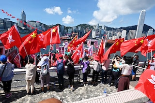 People wave Chinese and Hong Kong flags as fishing boats with banners and flags to mark the 25th anniversary of the Handover of Hong Kong from Britain to China sail through Hong Kong’s Victoria harbour on June 28, 2022. Image:&nbspPeter Parks / AFP