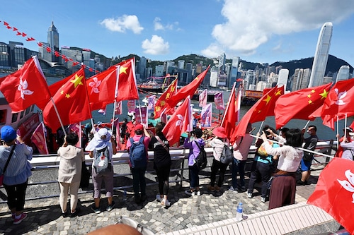 People wave Chinese and Hong Kong flags as fishing boats with banners and flags to mark the 25th anniversary of the Handover of Hong Kong from Britain to China sail through Hong Kong’s Victoria harbour on June 28, 2022. Image:&nbspPeter Parks / AFP