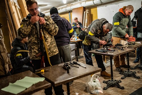 Volunteers are armed at a base where Ukrainian men and women received rapid military training, from intelligence to weapons, in Kyiv on Feb. 28, 2022. If there is one overriding emotion gripping Ukraine right now, it is hate much of the bitterness is directed at Russian President Vladimir Putin, but Ukrainians also chastise ordinary Russians, calling them complicit. (Lynsey Addario/The New York Times)