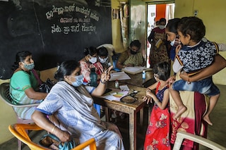 A pediatrician (2L) talks with a mother as she conducts a general health checkup on children at a government rural child health care centre at Gollahalli village on the outskirts of Bangalore on July 1, 2021. (Photo by Manjunath Kiran / AFP)