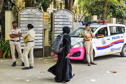 A woman wearing a veil walks past police guarding outside a school in Bangalore on March 15, 2022, after court upheld a local ban on the hijab in classrooms.