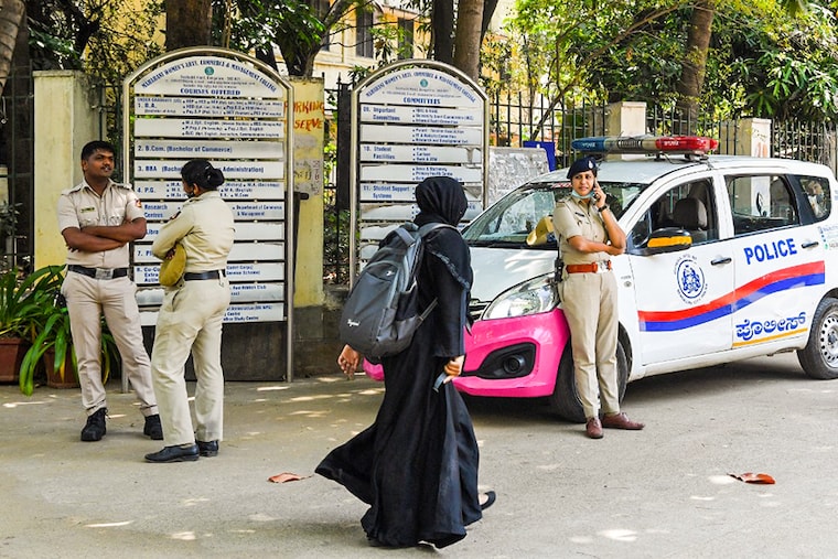 A woman wearing a veil walks past police guarding outside a school in Bangalore on March 15, 2022, after court upheld a local ban on the hijab in classrooms.